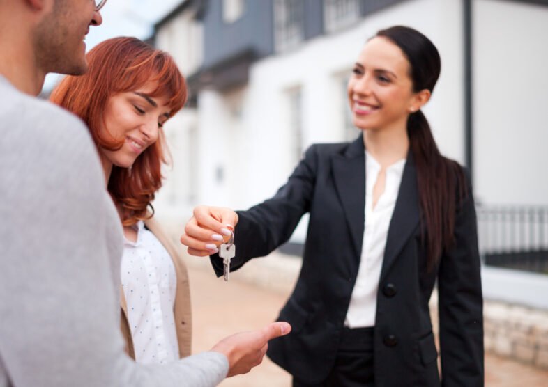 Real,Estate,Agent,Giving,Keys,For,New,House,To,Young